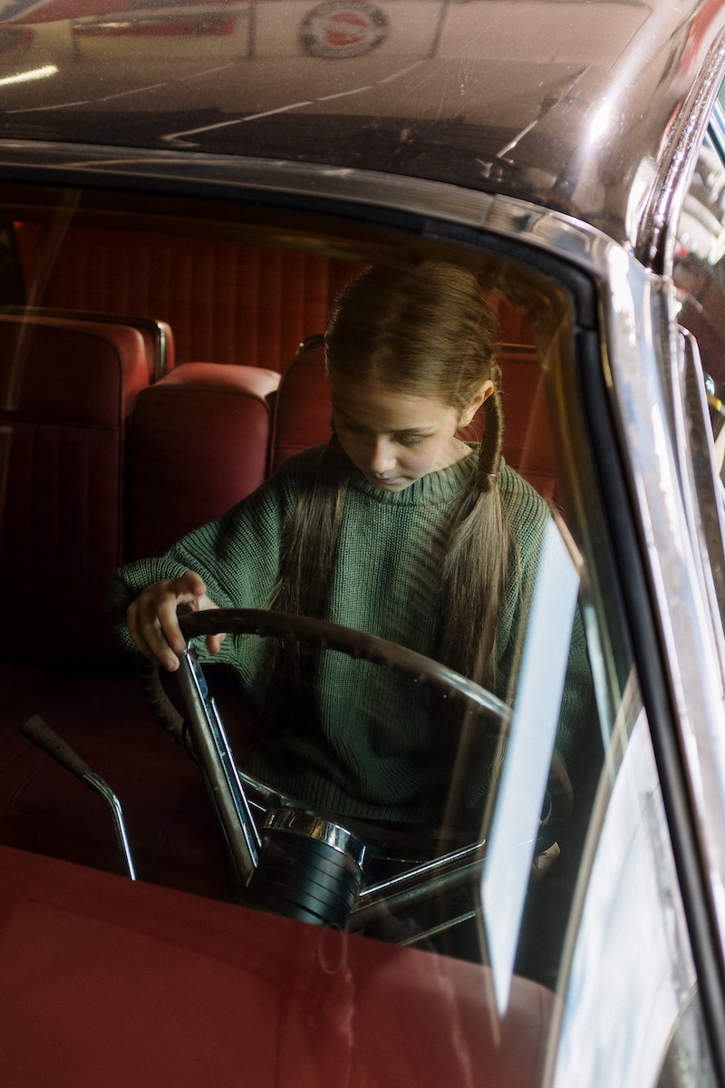 Boy in Green Sweater Sitting on Red Car Seat