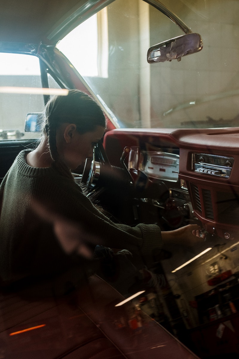 Woman in Gray Sweater Sitting on Black and Red Car