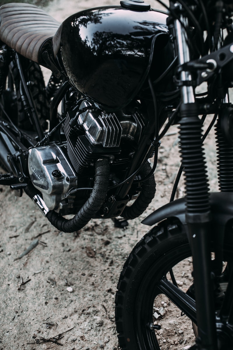 Black shiny motorcycle parked on sandy road in summer day in nature outside