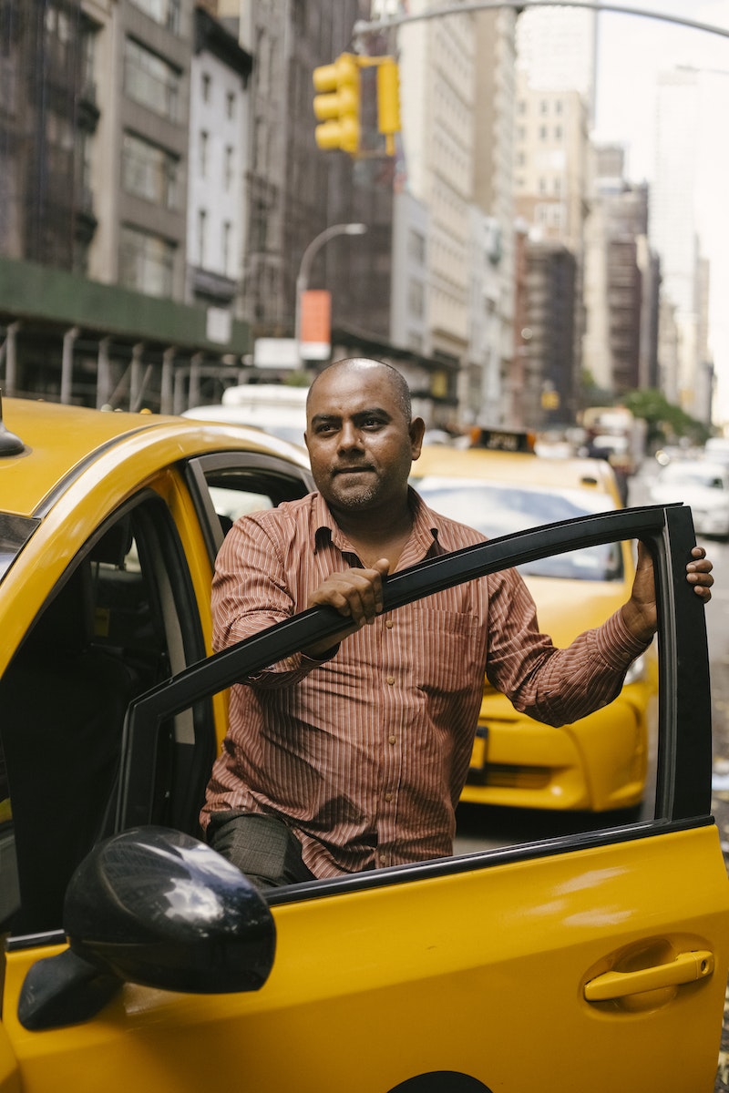 Ethnic man getting into yellow taxi