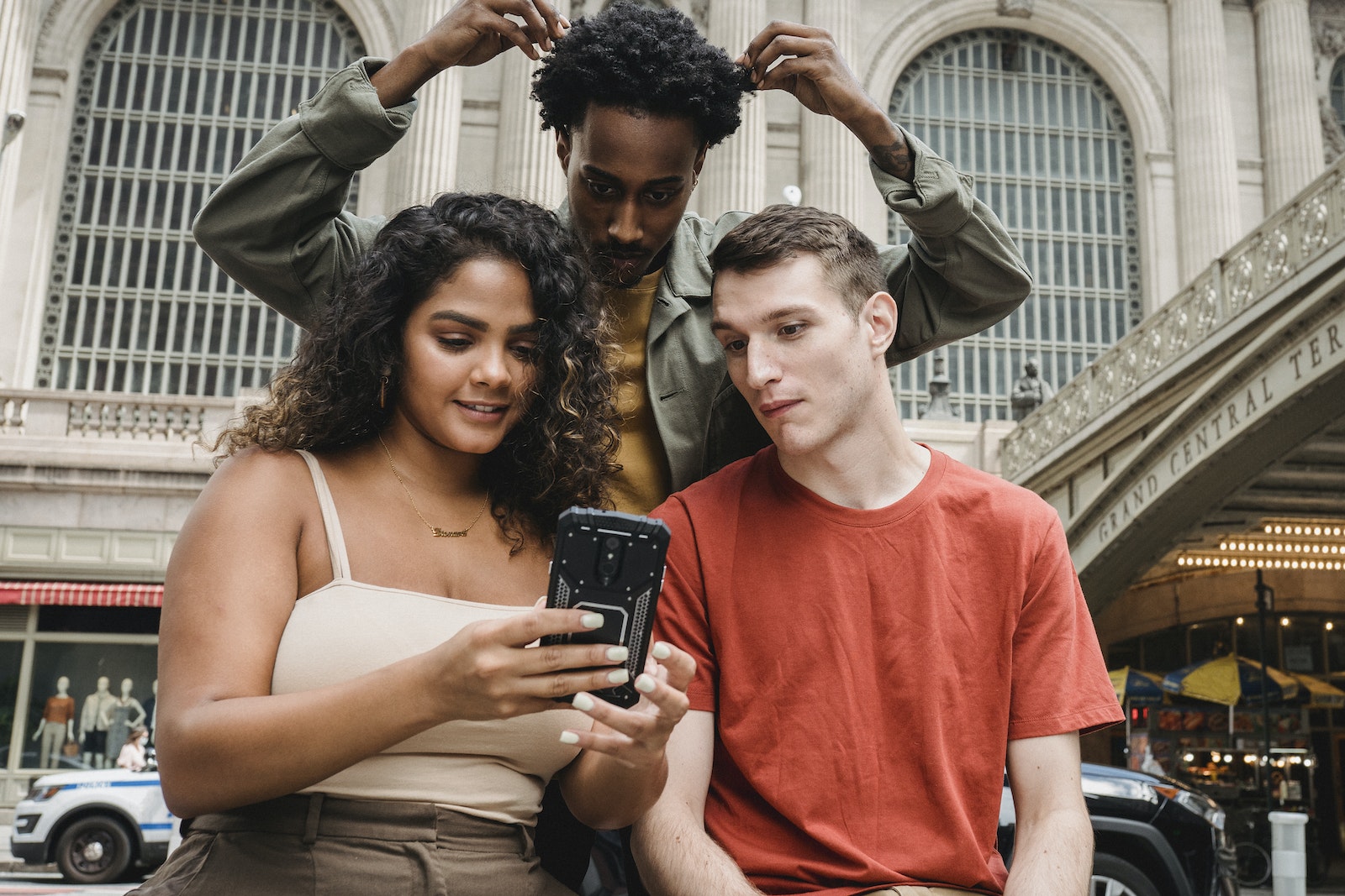 Focused multiethnic friends browsing smartphone on street