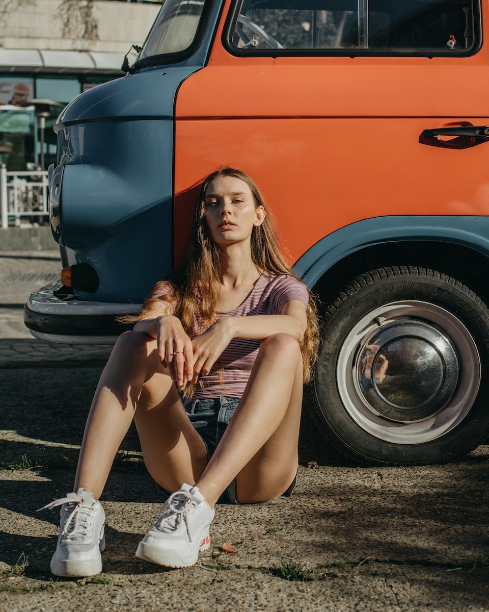 Young women sitting near car and looking at camera